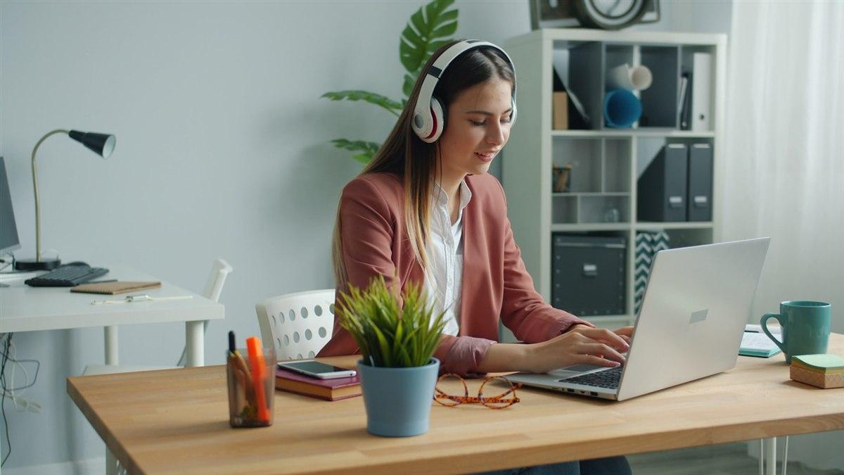 職場女性戴著耳機在筆電前上英語課程,專注進行口說練習